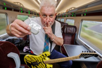 Robb-Weir-onboard-LNER-train-with-guitar-calling-for-quiet_cropped-scaled.jpg